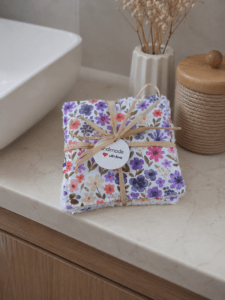 Lot de 7 cotons lavables artisanaux motif floral Rozen dans les tons roses, violets et verts, présenté avec son lien en raphia.
