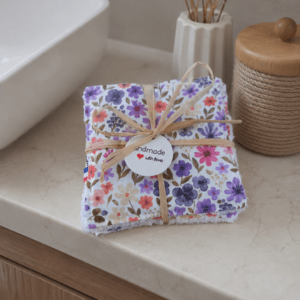 Lot de 7 cotons lavables artisanaux motif floral Rozen dans les tons roses, violets et verts, présenté avec son lien en raphia.